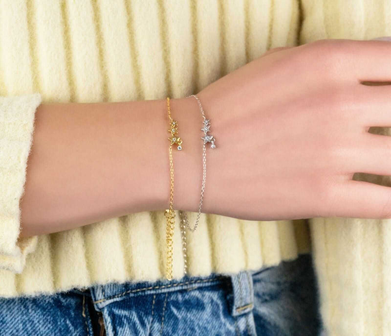 Stars bracelet in 925 sterling silver and 14K gold plated, featuring tiny star charms, worn on a wrist.