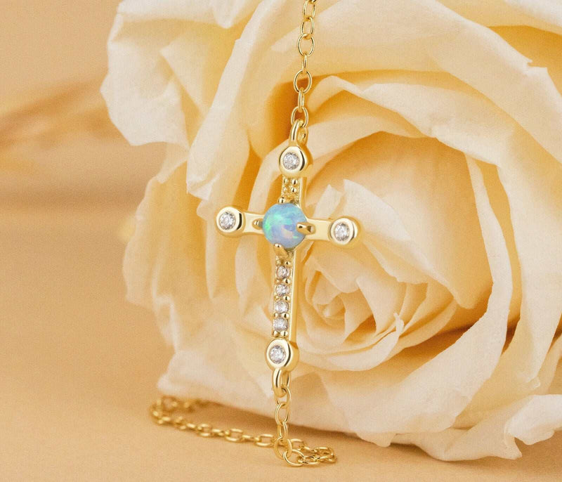 Sterling silver cross Jesus bracelet with 18K gold plating on a cable chain, displayed beside a rose.