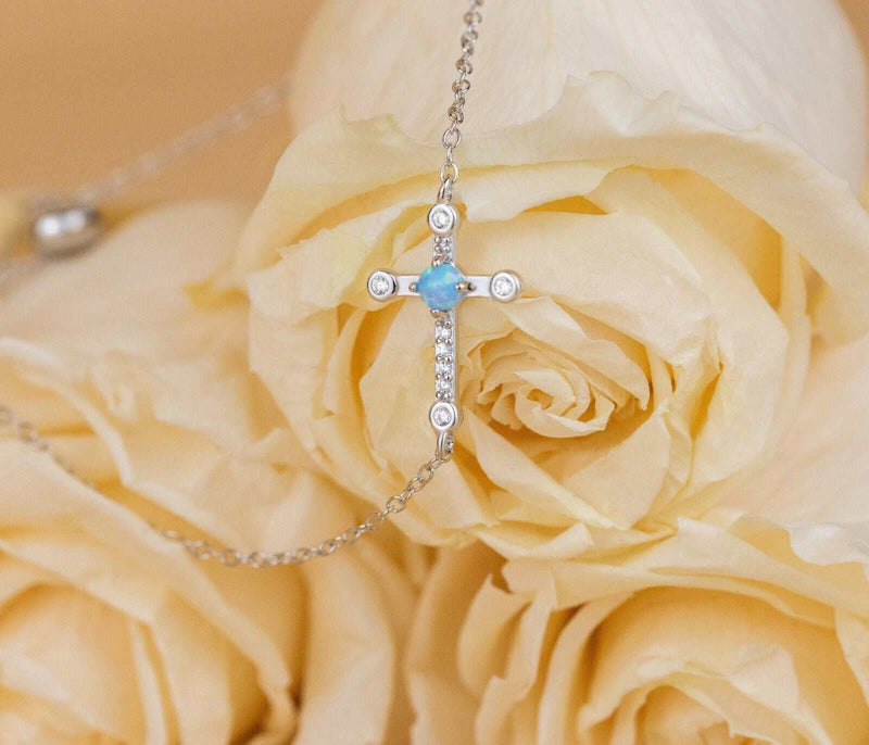 Sterling silver cross Jesus bracelet with 18K gold plating displayed on ivory roses.