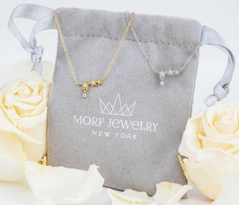 Stars bracelet in 925 sterling silver, 14K gold plated, with tiny charms, displayed on a gift pouch with roses.