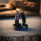 Hammered black nebula meteorite ring with galaxy blue sandstone inlay, 6mm wide, displayed on wood.