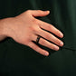 Hand wearing an 8mm Damascus Meteorite & Crushed Gold Ring, featuring a black steel hammered band with a unique striped pattern.