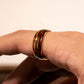 Guitar String Whiskey Barrel Ring with rose gold, tungsten, and whiskey barrel wood inlay on hand.