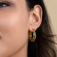 Gold-plated Mirage Twisted Hoop Earrings on woman.