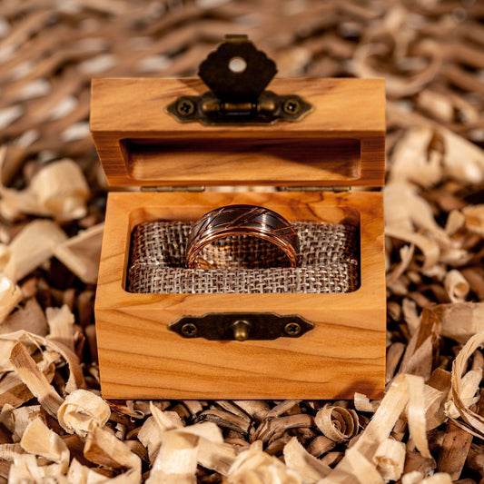 Rose gold men's wedding band in a wooden box, featuring a hammered tungsten carbide finish by Morf Jewelry.